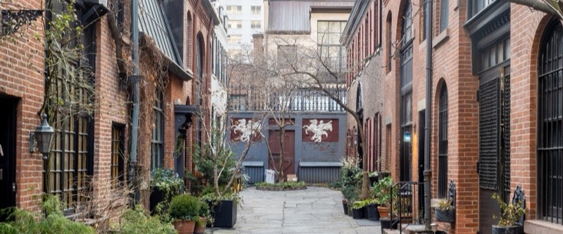 Brick carriage houses with planters facing the flagstone lane of Sniffen Court, Murray Hill, Manhattan